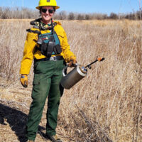Danielle Howard holds a drip torch while starting a prescribed burn.