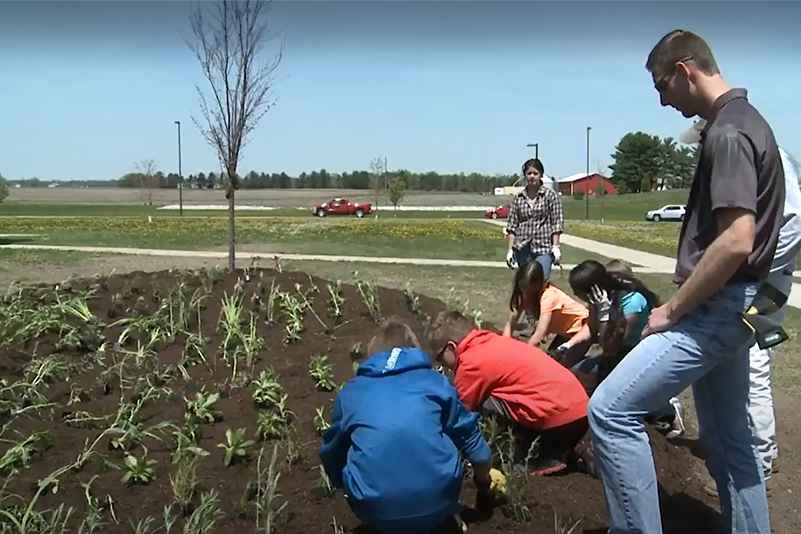 A group of kids with a teacher explaining rainscape